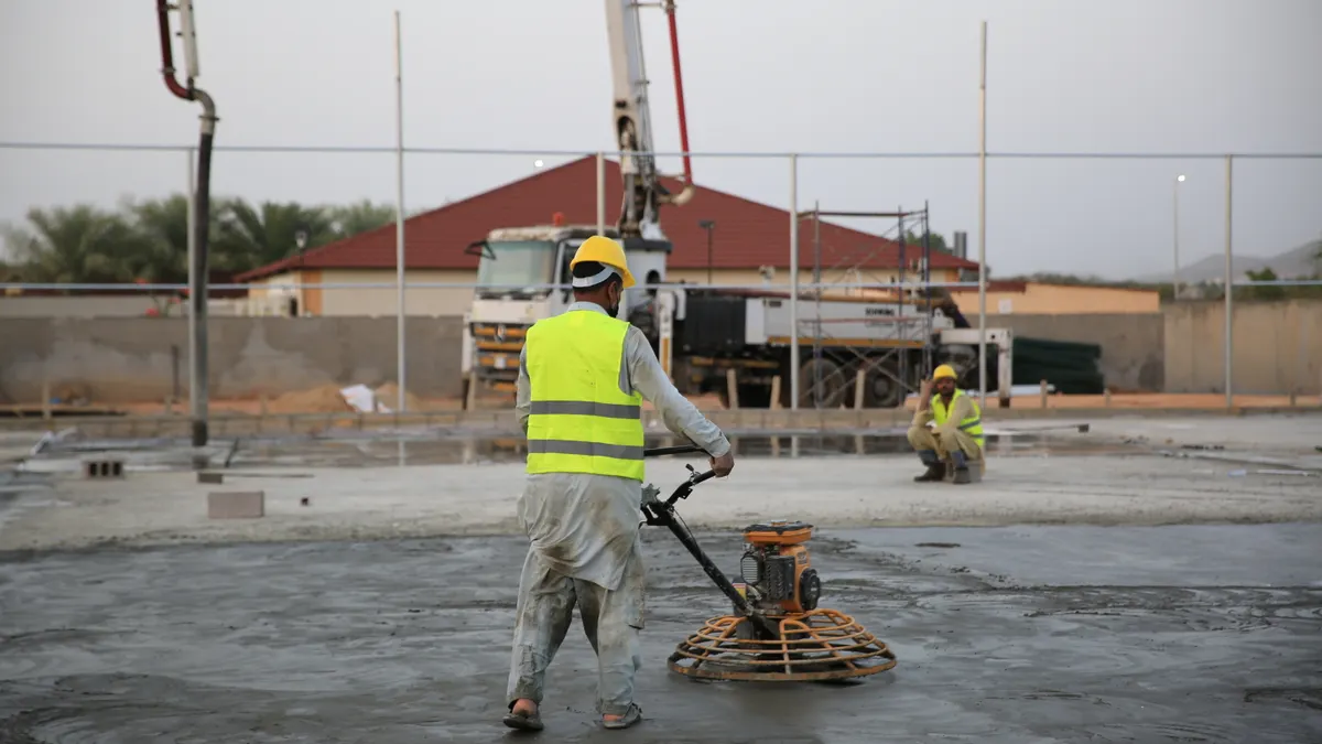 Worker power-troweling a concrete slab