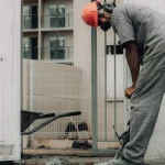 Worker breaking concrete beside a doorway