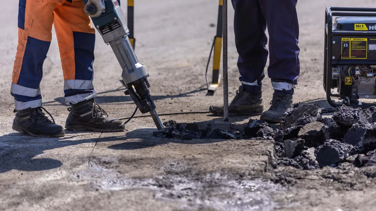 Can You Lift a Garage Floor Slab Without Replacing It? Worker jackhammering broken pavement