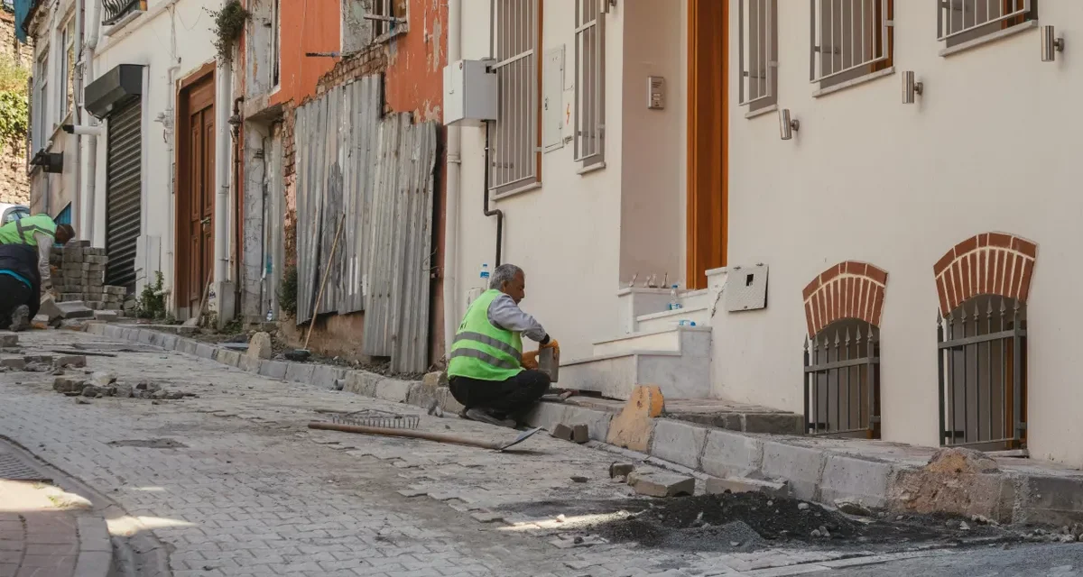 Worker repairing a sidewalk beside row buildings
