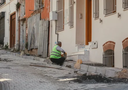 Worker repairing a sidewalk beside row buildings