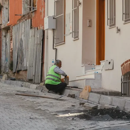 Worker repairing a sidewalk beside row buildings