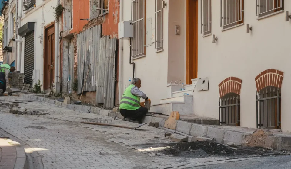 Worker repairing a sidewalk beside row buildings